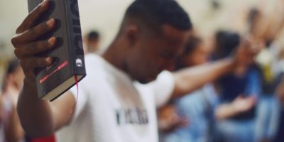 selective focus photography of man holding Holy Bible
